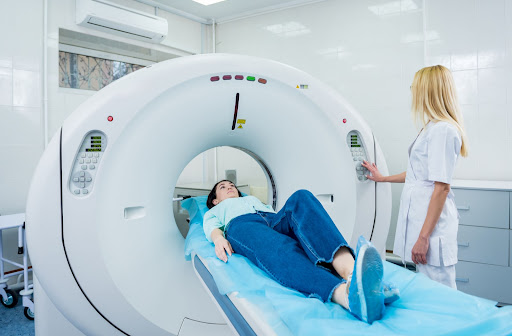 A woman about to have a CT scan done, while a female nurse operates the machine