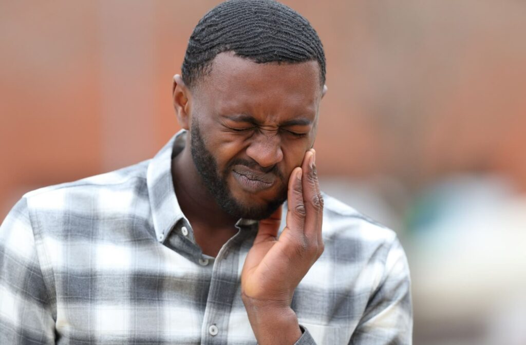 An image of an adult in discomfort, holding his jaw in pain, suggesting a possible issue with his teeth or TMJ.