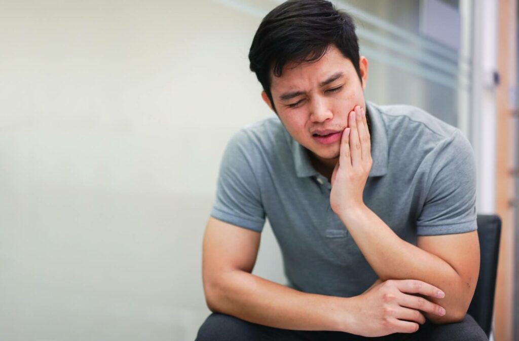 A patient holding their jaw in discomfort due to an infected wisdom tooth.