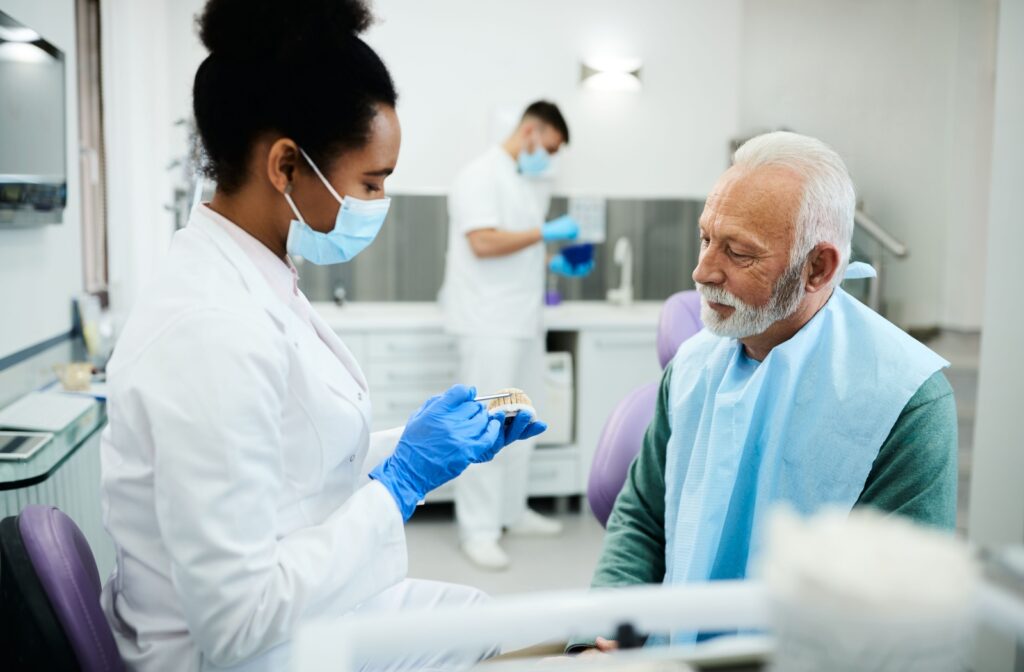 An oral surgeon using model teeth to explain the requirements for dental implant candidacy to a patient.